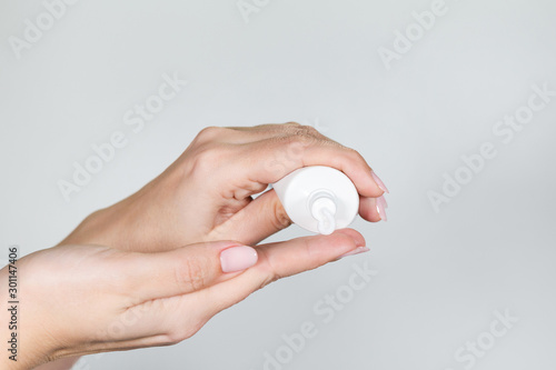 Photographie Closeup view of two white female hands holding plastic tube with white cream