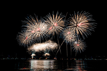 Amazing beautiful colorful fireworks display on celebration night, showing on the sea beach with multi color of reflection on water