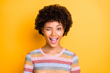Wall Mural - Close up photo of beautiful dark skin curly lady playful mood winking one eye see handsome guy wear casual striped t-shirt isolated yellow background