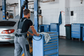 Wall Mural - Car service. Male mechanic use different tools to repair broken automobile in garage