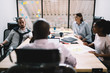 © BullRun - Back view of male director talking to employee about productive strategy for working time during conference in office, collaborative process of intelligent multicultural coworkers sitting at desktop