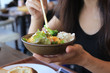 © wothan - chiba, japan, 11/04/2019 , Woman eating  a salad on a bowl with chopsticks.