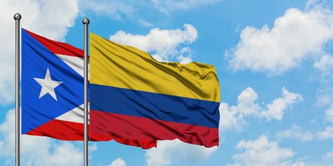 Puerto Rico and Colombia flag waving in the wind against white cloudy blue sky together. Diplomacy concept, international relations.