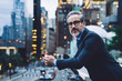 © BullRun - Mature businessman holding phone against background of city street