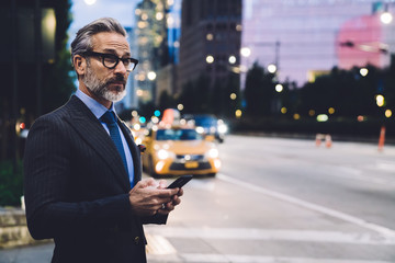 Wall Mural - Middle aged businessman holding smartphone against New York road