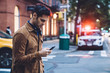© BullRun - Thoughtful ethnic young man in jacket texting and walking along street