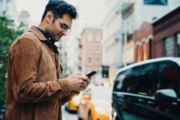 Ethnic young man texting on street