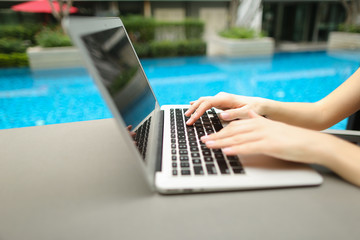 Wall Mural - close up woman hands pressing keyboard on laptop sunny day swimm