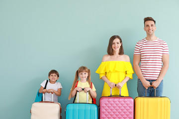 Wall Mural - Happy family with luggage on color background