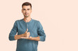 © Pixel-Shot - Young deaf mute man using sign language on color background