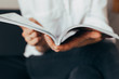 © Nana_studio - Beautiful female hands hold an open book or magazine in the room