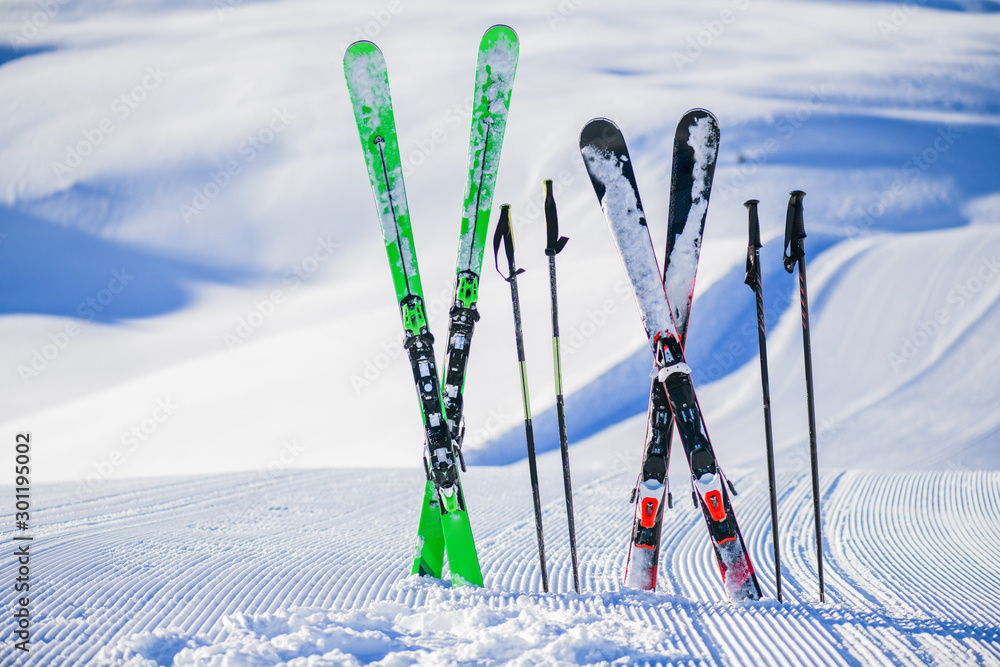 Skis in snow in winter season, mountains and ski items or equipments on the top in dolomites, - obrazy, fototapety, plakaty 