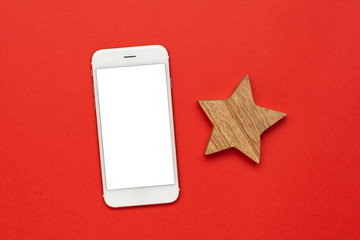 Wall Mural - Mobile phone with wooden Christmas tree decoration on red color paper background