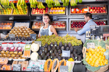 Portrait of welcoming female shop assistant and working male seller in fruit shop