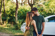 © standret - Near white colored car. Beautiful young couple have a good time in the forest at daytime