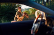 © standret - View through the car's window. Beautiful young couple have a good time in the forest at daytime