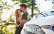 © standret - Front part of white car. Beautiful young couple have a good time in the forest at daytime