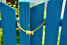A Blue Gate Post And Fence Picket Tied Together Illustrate The Abstract Concept Of Love, Togetherness And Family. 
