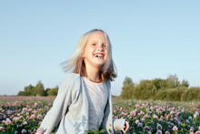 Portrait Of A Smiling Girl Standing On A Clover Field