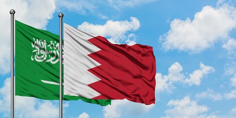 Wall Mural - Saudi Arabia and Bahrain flag waving in the wind against white cloudy blue sky together. Diplomacy concept, international relations.