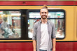 © WILLIAM PERUGINI/Westend61 - Young man at train station with blurred train as background