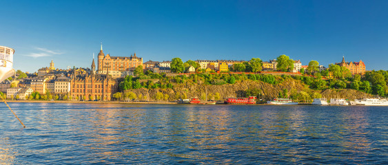 Wall Mural - Panoramic view of Sodermalm island with Multicolor colorful fishing boats and ships on Lake Malaren, typical traditional buildings, Monteliusvagen view platform, clear blue sky, Stockholm, Sweden