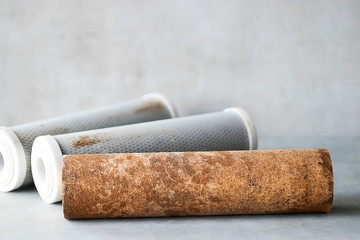 Old used cartridges for a water filter on a gray background.