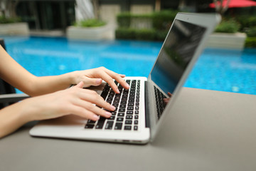 Wall Mural - close up woman hands pressing keyboard on laptop sunny day swimm