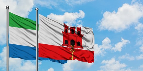 Sierra Leone and Gibraltar flag waving in the wind against white cloudy blue sky together. Diplomacy concept, international relations.