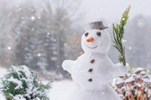 Lovely Smiling Snowman In The Winter Garden Within A Heavy Snowfall