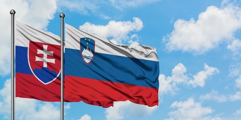 Slovakia and Slovenia flag waving in the wind against white cloudy blue sky together. Diplomacy concept, international relations.