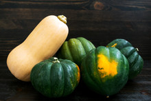 Rustic Grouping Of Acorn Squash And A Butternut Squash On A Dark Wood Background