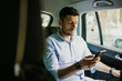 © F8  \ Suport Ukraine - Young man texting with client on phone while trip on backseat of office car