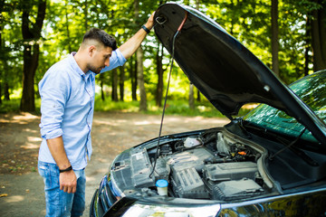 Young man on the road having problem with a car. Broken down car on the road. Traveling problem in road.