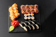 Various kinds of sushi served on black background. Sushi menu for Japanese food. Japanese sushi set. Rolls with tuna, salmon, shrimp, crab and avocado. Horizontal photo.