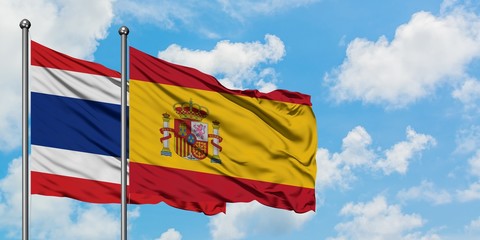 Thailand and Spain flag waving in the wind against white cloudy blue sky together. Diplomacy concept, international relations.