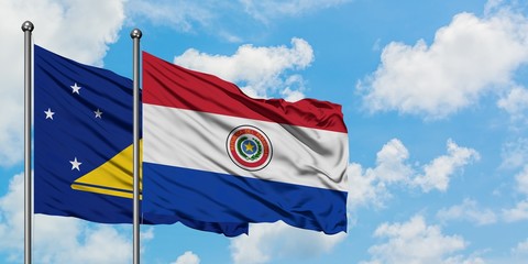 Tokelau and Paraguay flag waving in the wind against white cloudy blue sky together. Diplomacy concept, international relations.
