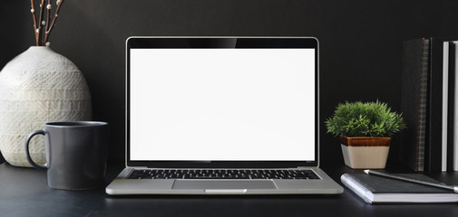 open blank screen laptop computer in dark modern office room with office supplies