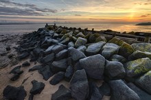 Sunset At The Beach Covered In Rocks Of Different Shapes And Sizes