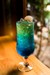 glass of blue cocktail decorated  on the bar counter.