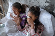 © zinkevych - Two sisters lying in bed and sneezing after catching flu