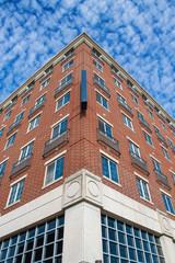 Wall Mural - Perspective of tall brick attractive middle America business building from corner with crazy puffy blu of tall brick attractive middle America business building from corner with crazy puffy blue cloud