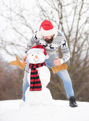 Wall Mural - Good time. bearded man build snowman. winter season activity. its christmas. winter holiday outdoor. warm sweater in cold weather. man santa hat play with snow. happy hipster ready to celebrate xmas