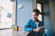 © BullRun - Cheerful african american woman dressed in jeans jacket using electronic headphones and smartphone internet connection for listening positive audio book, happy girl enjoying leisure time indoors