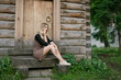 © Vladimir Arndt - Young woman sitting near a wooden house.