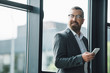 © LIGHTFIELD STUDIOS - handsome businessman in formal wear and glasses holding smartphone