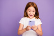 © deagreez - Photo of pretty small foxy lady holding telephone hands checking children blog excited with many new followers subscribers wear white t-shirt isolated purple background