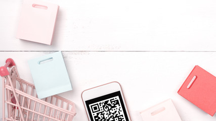 Abstract online shopping, mobile payment with QR code design concept element, colorful cart, paper bag on wooden table background, top view, flat lay