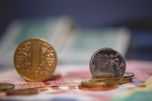 Macro Photo Of A Coin In 1 Ruble And One Hryvna On A Blurred Background Banknote In 200 Rubles. Silver Coin With The Symbol Of The Russian Ruble And Gold Hryvnia. Very Small Depth Of Field.