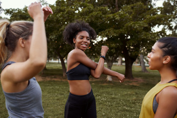 Poster - Group of fit active multiethnic female friends warming up before a workout in the park 